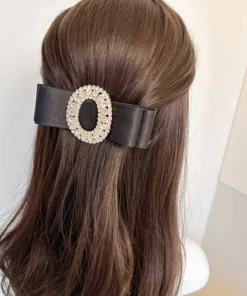 Une personne aux cheveux longs bruns coiffés à moitié relevés porte une grande Pince à Cheveux en Cristal Biscuit noire ornée d'un ornement en cristal de forme ovale.