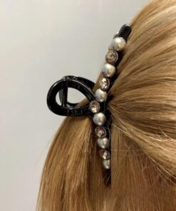 Un gros plan des cheveux blonds d'une personne, fixés avec des Pinces à cheveux en forme de crabe avec perles artificielles et strass.