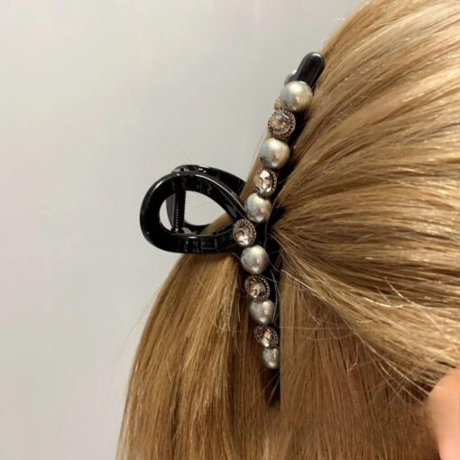 Un gros plan des cheveux blonds d'une personne, fixés avec des Pinces à cheveux en forme de crabe avec perles artificielles et strass.