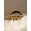 Un bracelet à maillons dorés avec une bande noire, reposant sur une surface en pierre de couleur claire, allie harmonieusement style et sophistication, parfait pour ceux qui recherchent l'accessoire parfait.