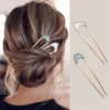 Une femme avec une coiffure en chignon bas fixée avec l'Épingle à Cheveux en Forme de U en Métal pour Femmes en or et blanc. Deux épingles à cheveux identiques, élégamment travaillées en forme de U, sont présentées séparément à droite.