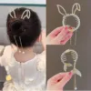 Cheveux de femme coiffés en chignon avec des épingles à cheveux décoratives en forme d'aile d'ange brillantes. Le gros plan de l'accessoire montre ses détails en perles et sa structure en forme de peigne, parfait pour les femmes et les filles à la recherche d'une touche fantaisiste.