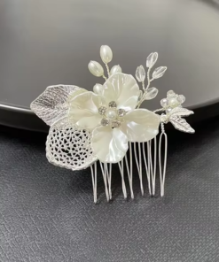 Une Peigne à cheveux en alliage d'or et brun, présentant des motifs floraux et de feuilles blancs ornés de perles et d'accents de cristal, placée sur une surface sombre.