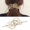 Les cheveux d'une femme sont attachés en arrière avec un Porte-Chignon Doré pour Femmes décoratif présentant un motif de boucle complexe. Un gros plan de l'épingle à cheveux est présenté ci-dessous.