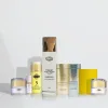 Le SET ÉCLAT NATUREL POUR TEINTS CARAMEL, composé de huit produits de soin dans des flacons et pots assortis, est présenté en rangée sur un fond blanc uni.