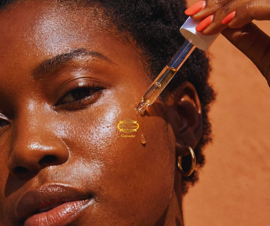 Une personne applique le sérum éclatant sur sa joue à l'aide d'un compte-gouttes, mettant en valeur Soins visage de Belle Nubian Canada sur un fond aux tons chauds.